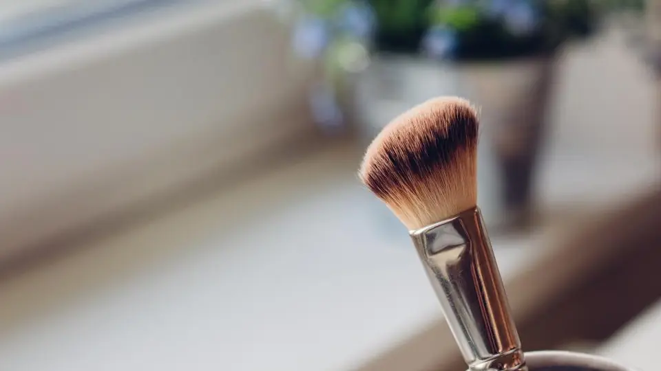 Pennello da trucco in un bicchiere vicino alla finestra